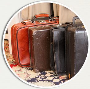 Resväskor och portföljer i närbild. Resväskan längst bort är röd med spännen och ett rejält handtag.